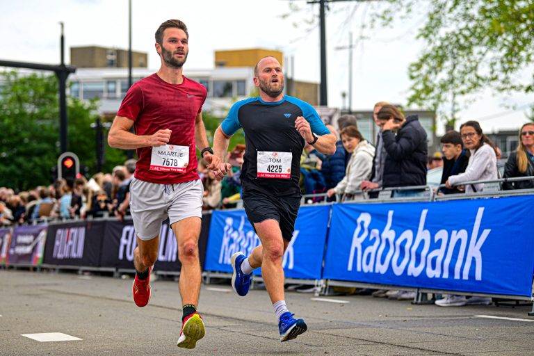 twee hardlopers tijdens de Tilburg Ten Miles met sponsor Rabobank in de achtergrond